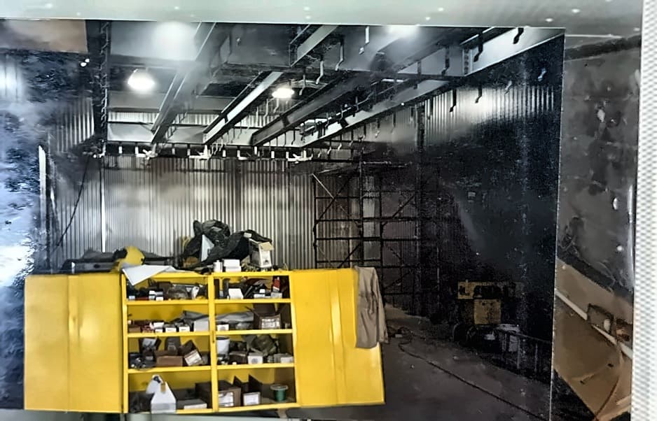 Interior fit-out with services run overhead and a yellow shop rack standing on the floor.