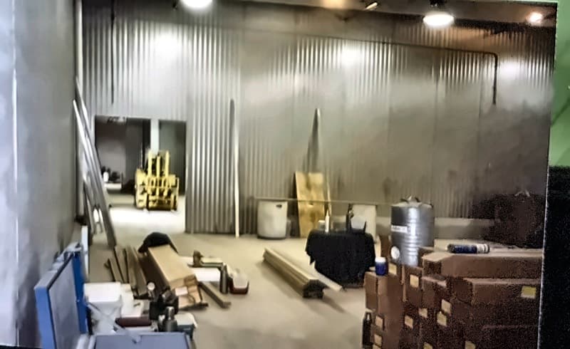 A finished metal-clad room with a forklift, a tank and cartons of material on the floor.