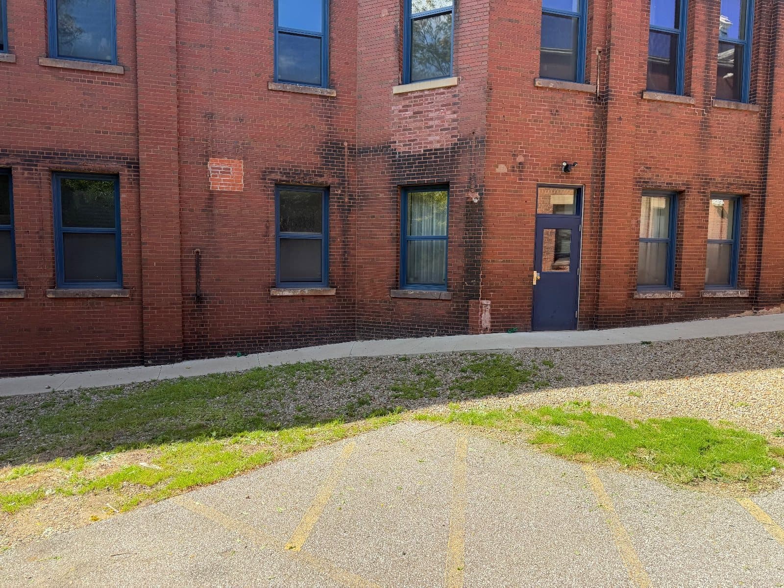 Ground-floor windows in dark blue frames along the red brick wall, beside a blue service door.
