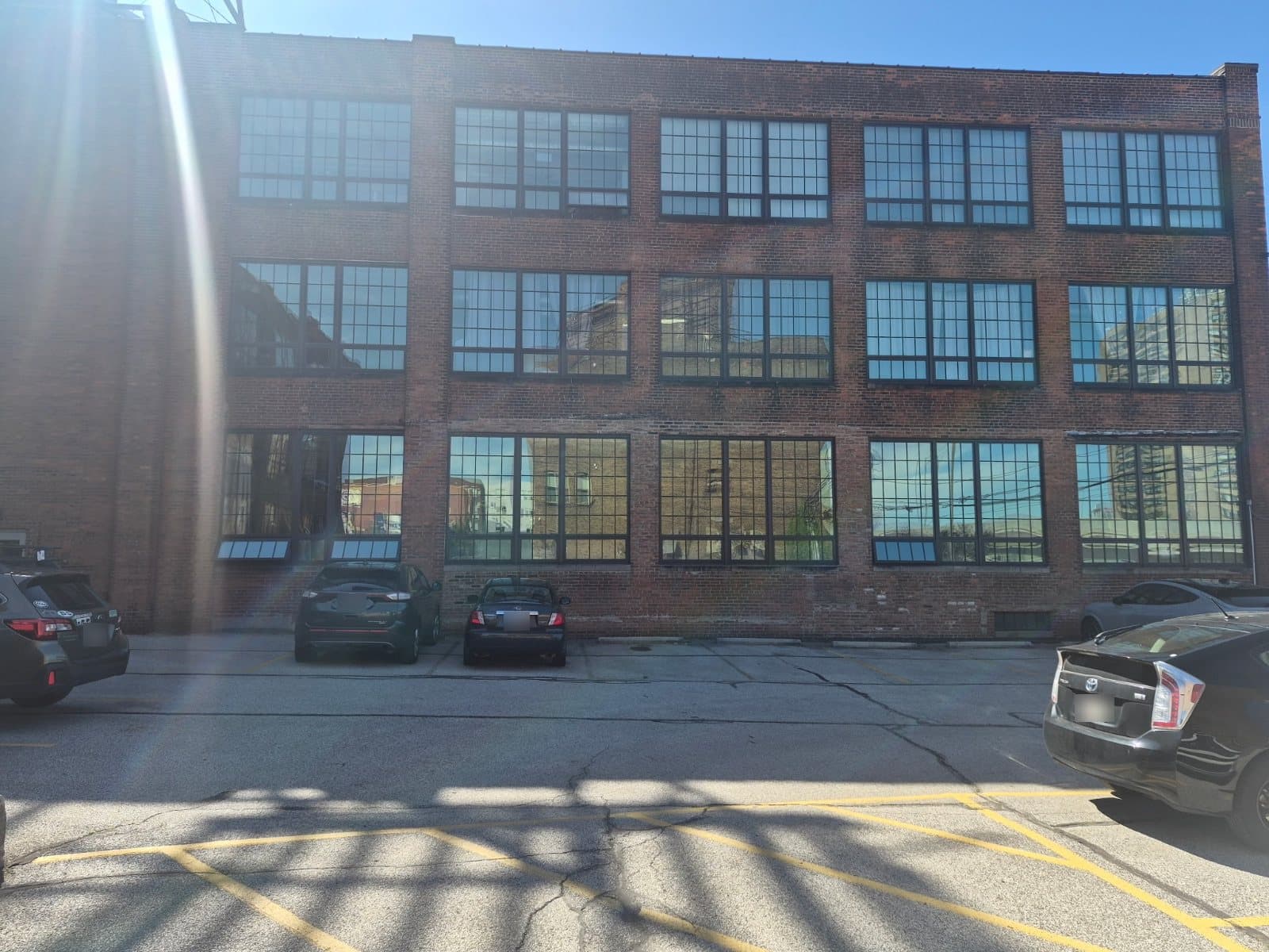 A brick warehouse elevation seen straight on, three floors of wide gridded windows, reflections in the glass.