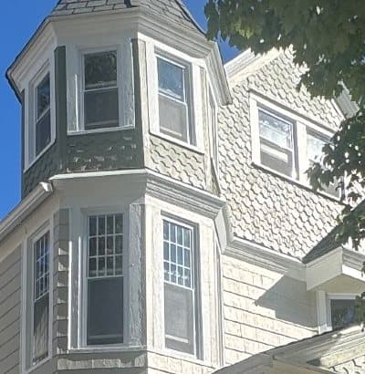 The corner tower close up: double-hung windows in each face on two floors, the lower ones with divided-lite upper sashes.
