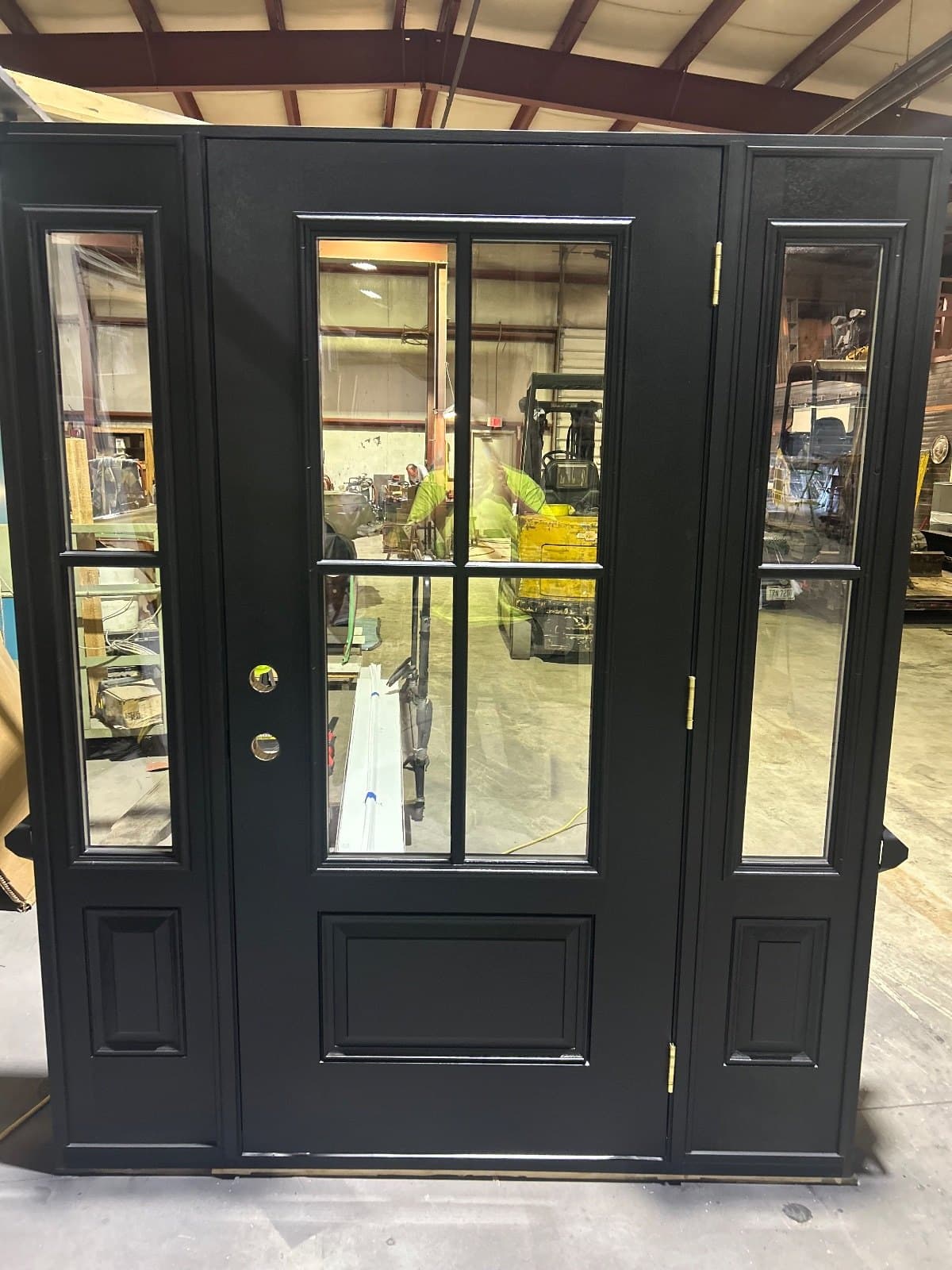 A black entry door flanked by two full sidelites with plain rectangular lites, standing in the shop.