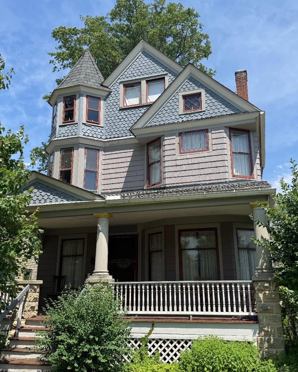 Before: the Victorian's street front in gray shingle, the tower, gables and porch windows in old red-trimmed sash, several with lace curtains.
