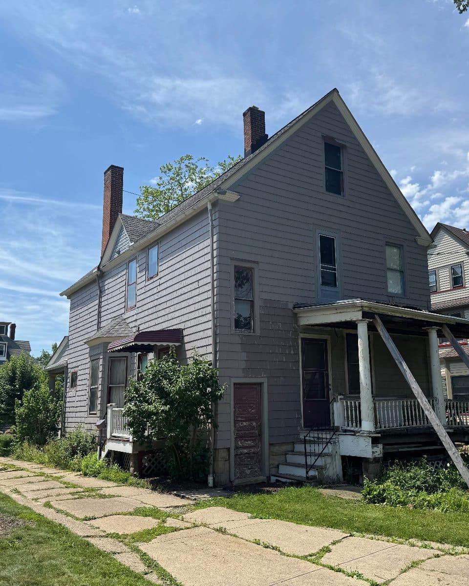 Before: the rear of the house in gray clapboard, a sagging back porch held up by timber props, the old windows above it.