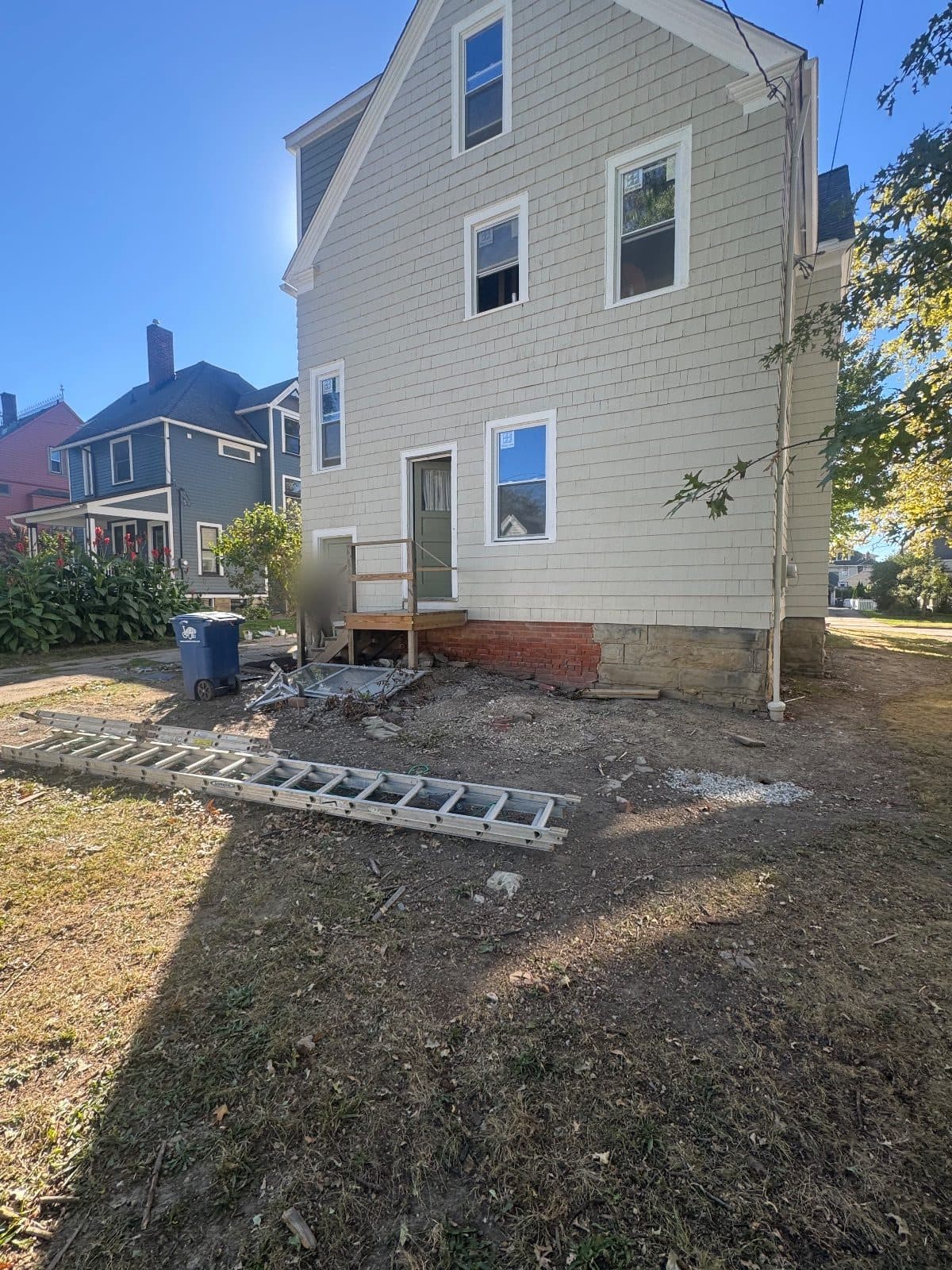 After: the rear gable straight on, sage siding, new white-framed windows on three floors, a new wooden back step.