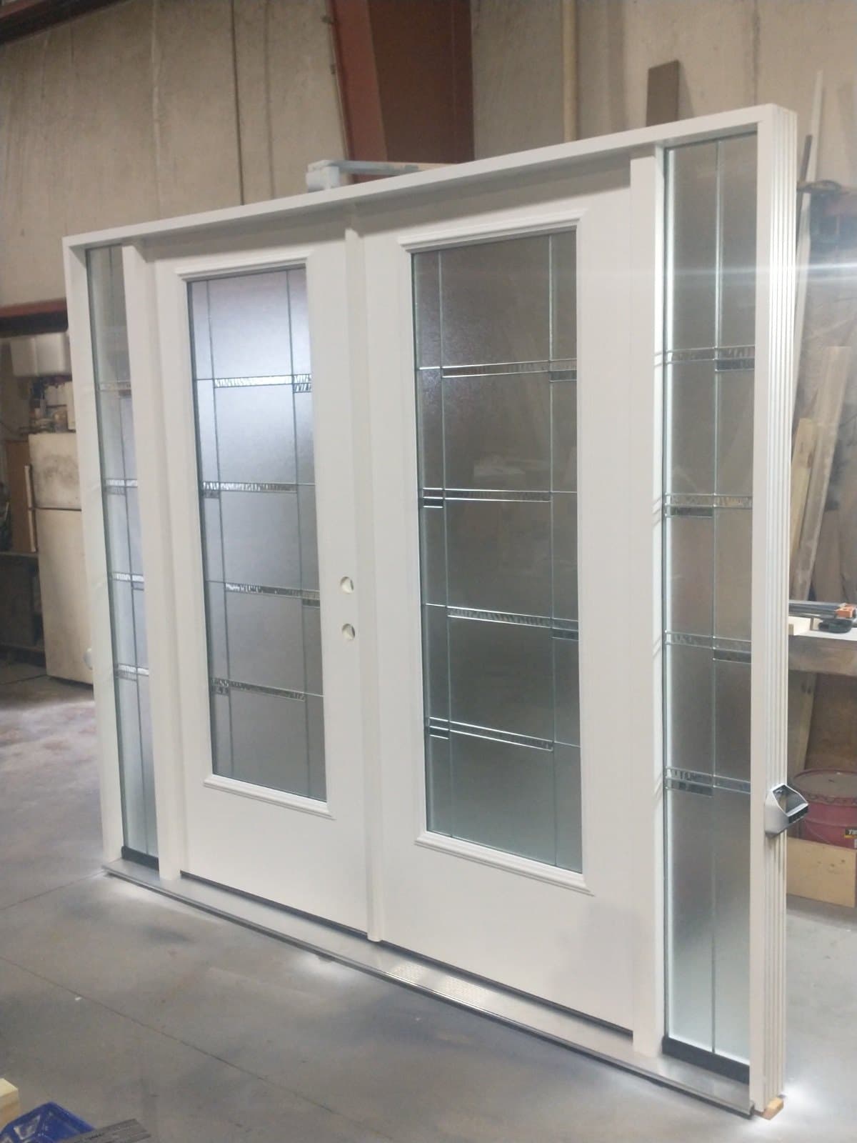 A white double door with reeded and frosted glass and slim sidelites, standing in the shop.
