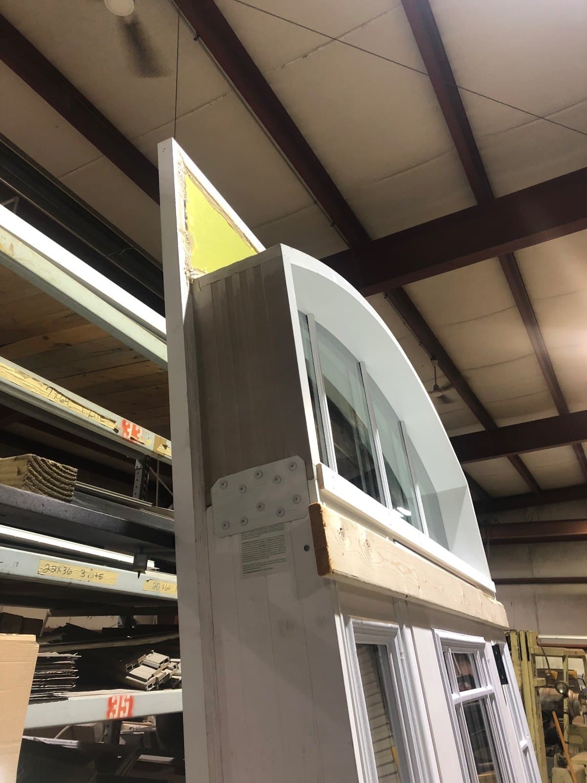 A curved arched transom unit stored on edge against the shop wall.