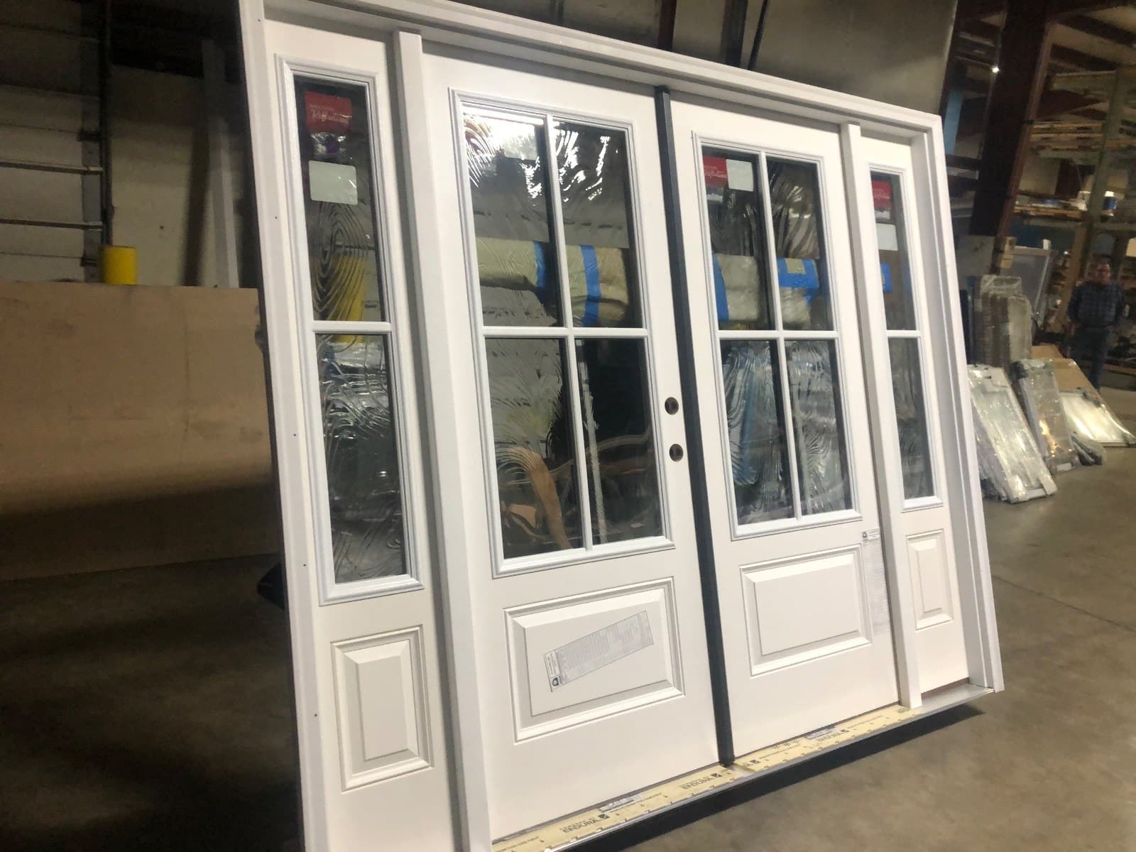 A white double door with divided lites and sidelites, standing in the shop.