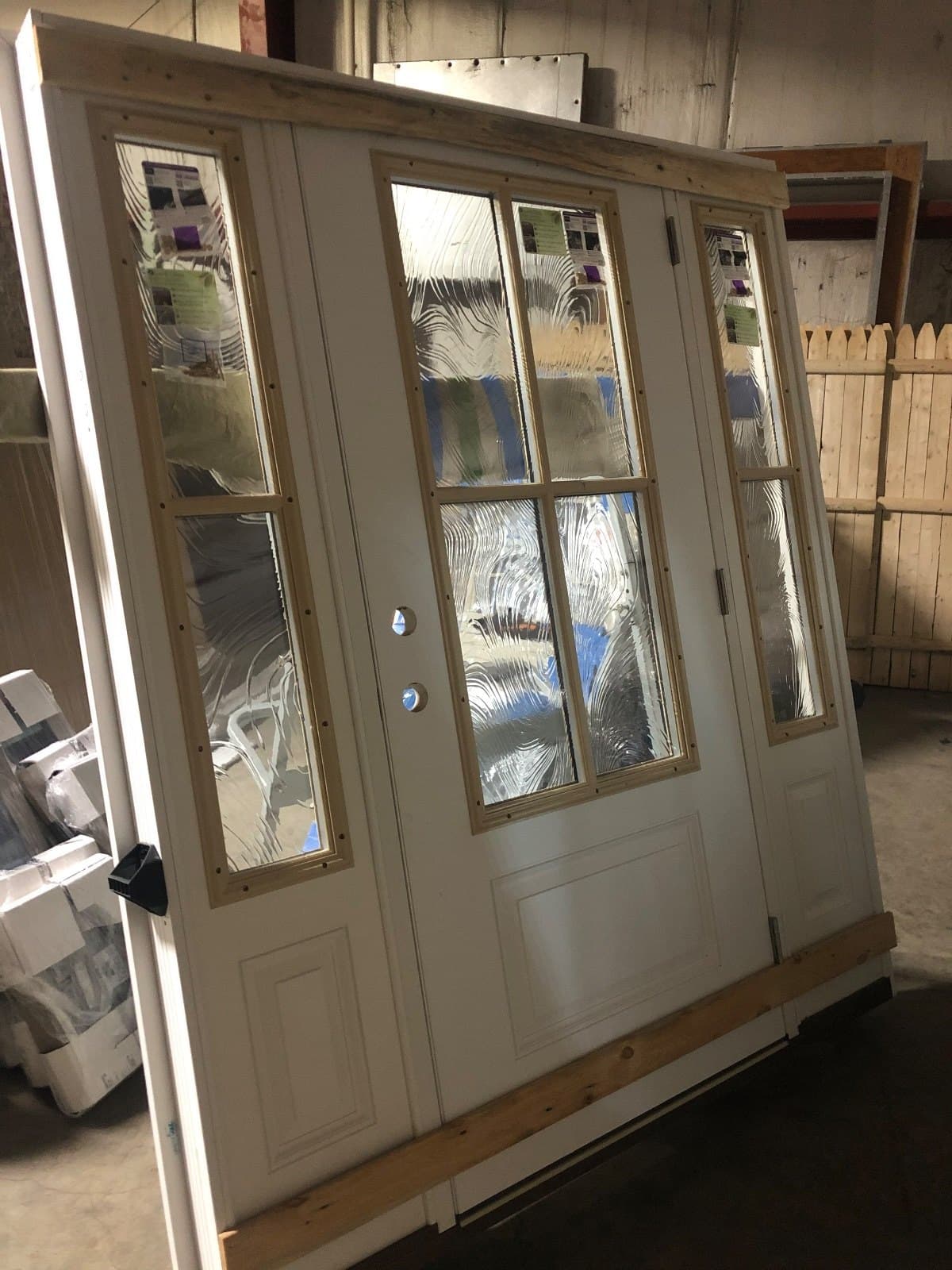 A cream double door with divided lites and matching sidelites, standing in the shop.