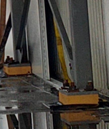 Two steel column base plates bolted down onto pale high-density urethane blocks that hold them clear of the floor slab beneath.