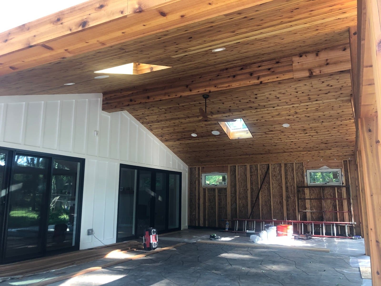 An interior still in framing, wood ceiling boards up and a wall of glass already set.