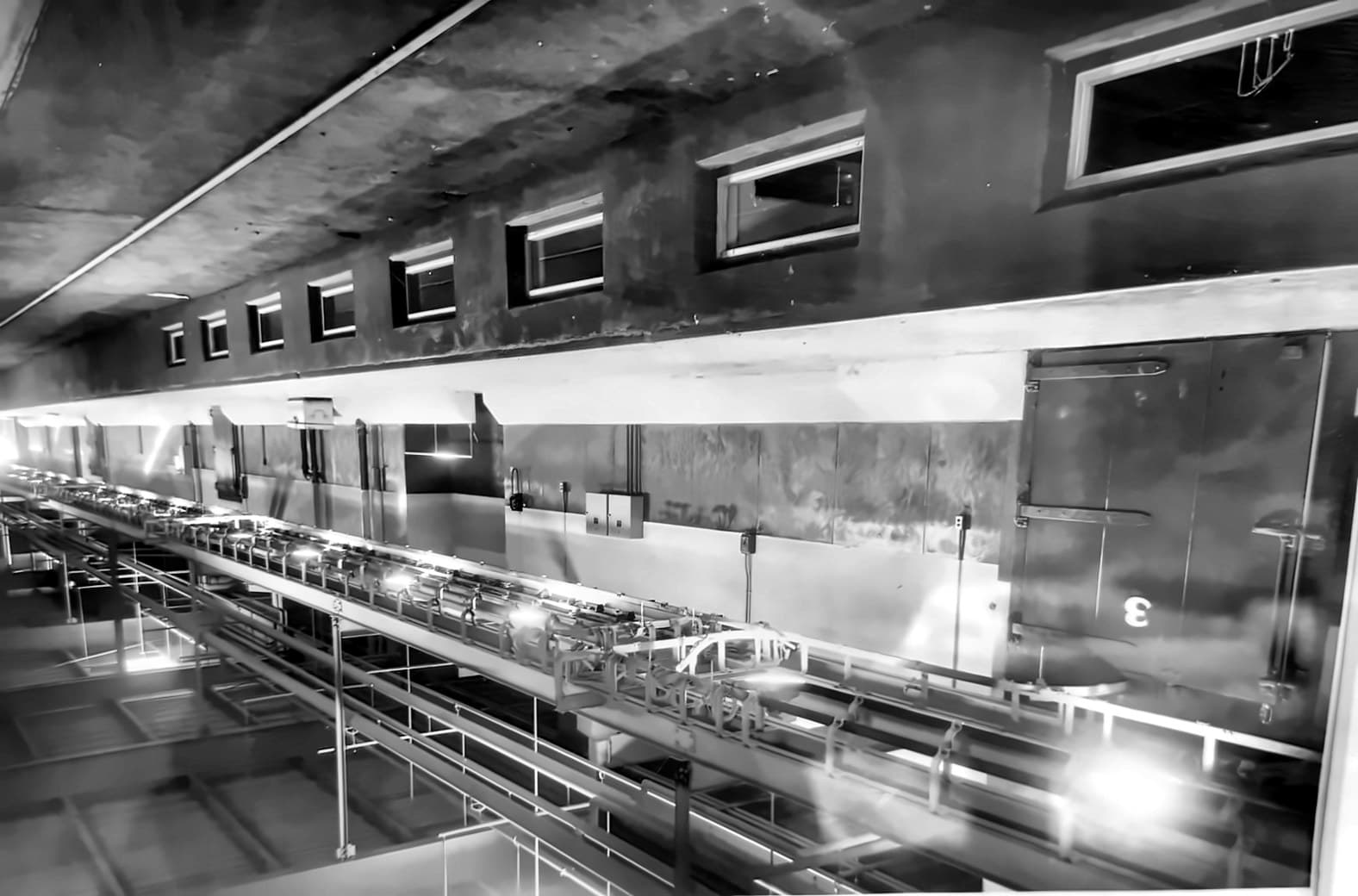 Processing line running the length of a plant, with cold-storage doors along the wall beside it.