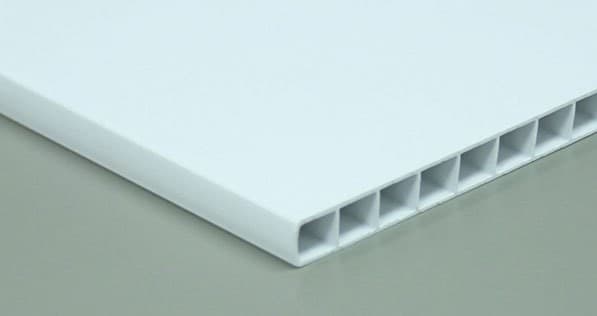 The cut edge of a white panel showing a row of rectangular voids through a fluted plastic core.