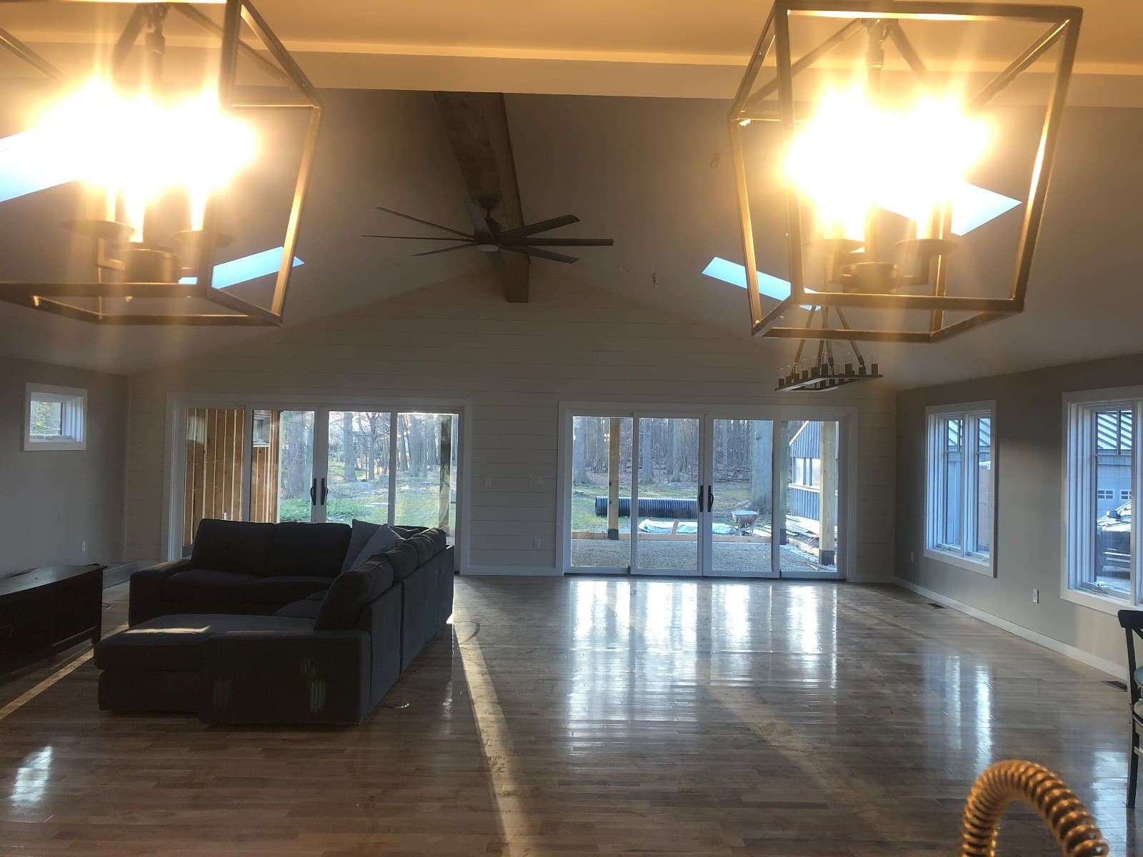 A living room with two lantern fixtures, a bank of windows and sliding doors, hardwood underfoot.