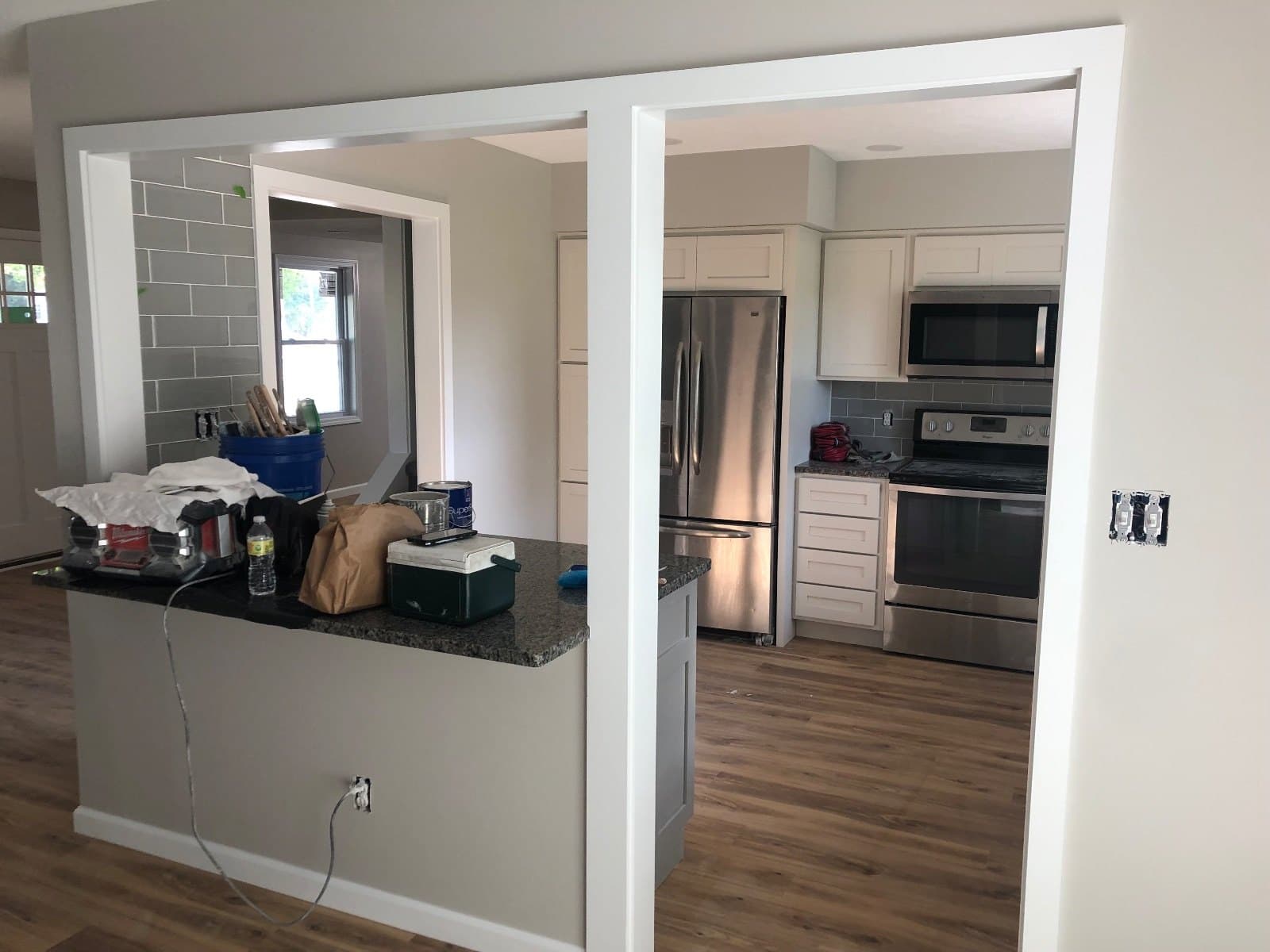 Two framed pass-through openings into a kitchen, materials on the counter and vinyl plank on both sides.