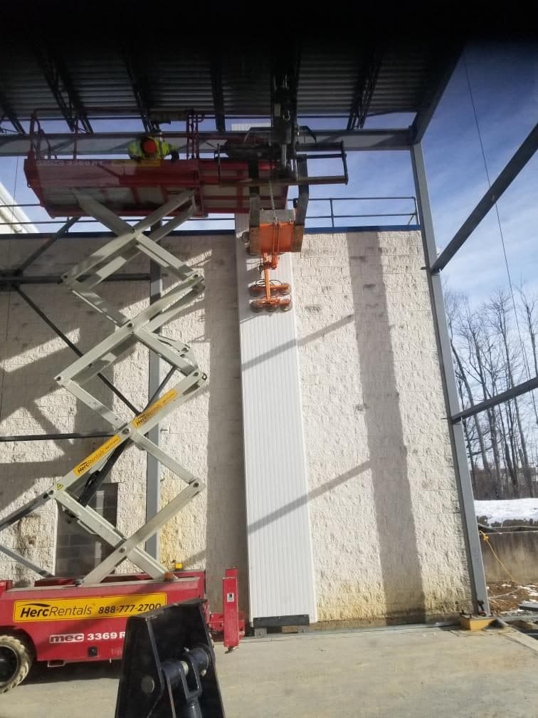 Insulated panel being set against the frame from a scissor lift.