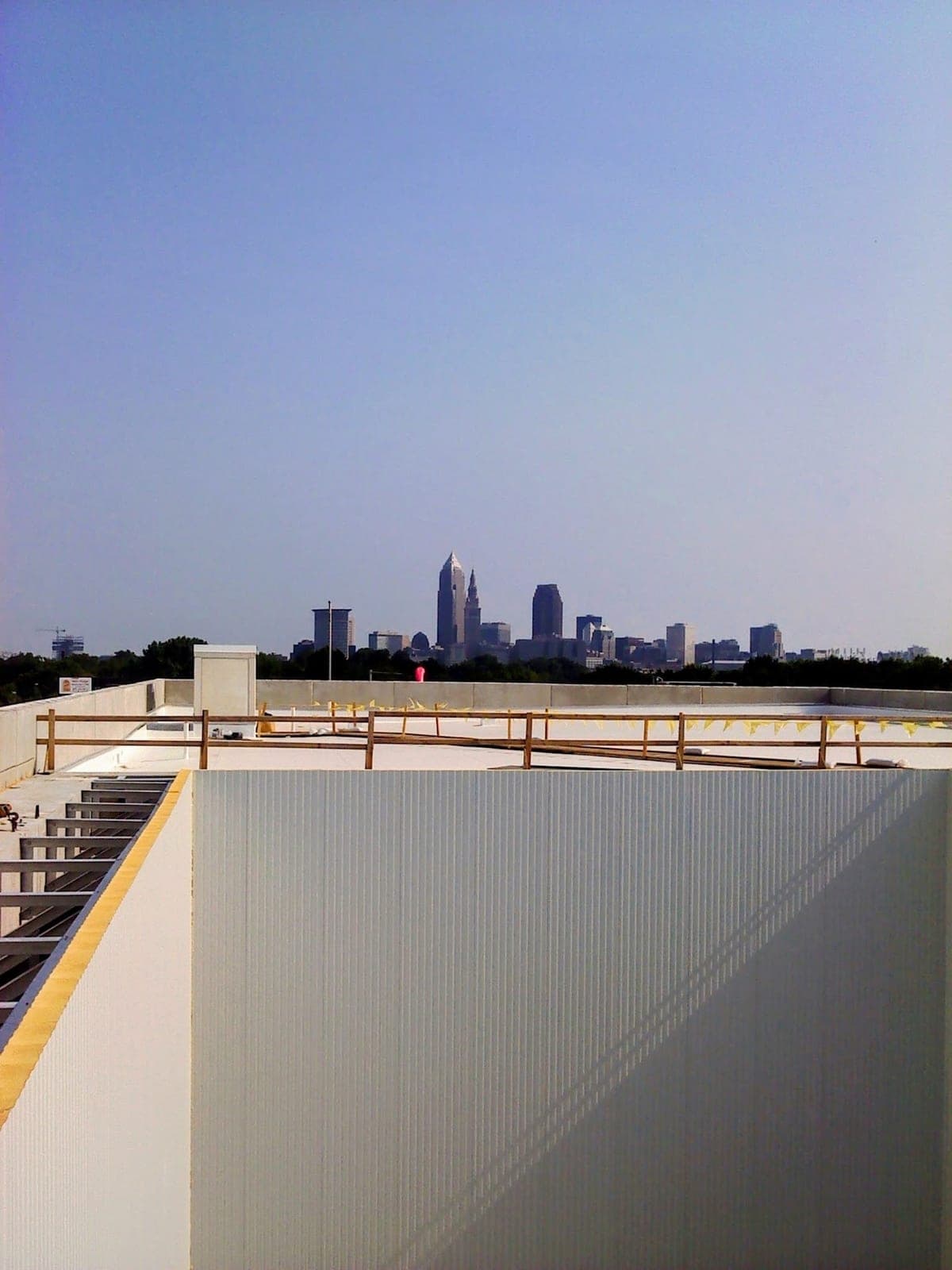 A new white insulated panel wall standing on a building roof, the Cleveland, Ohio skyline beyond it under a clear sky.