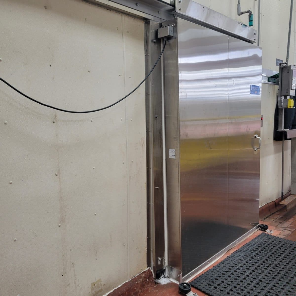 Stainless steel sliding freezer door, open, on a spiral freezer line inside a food plant.