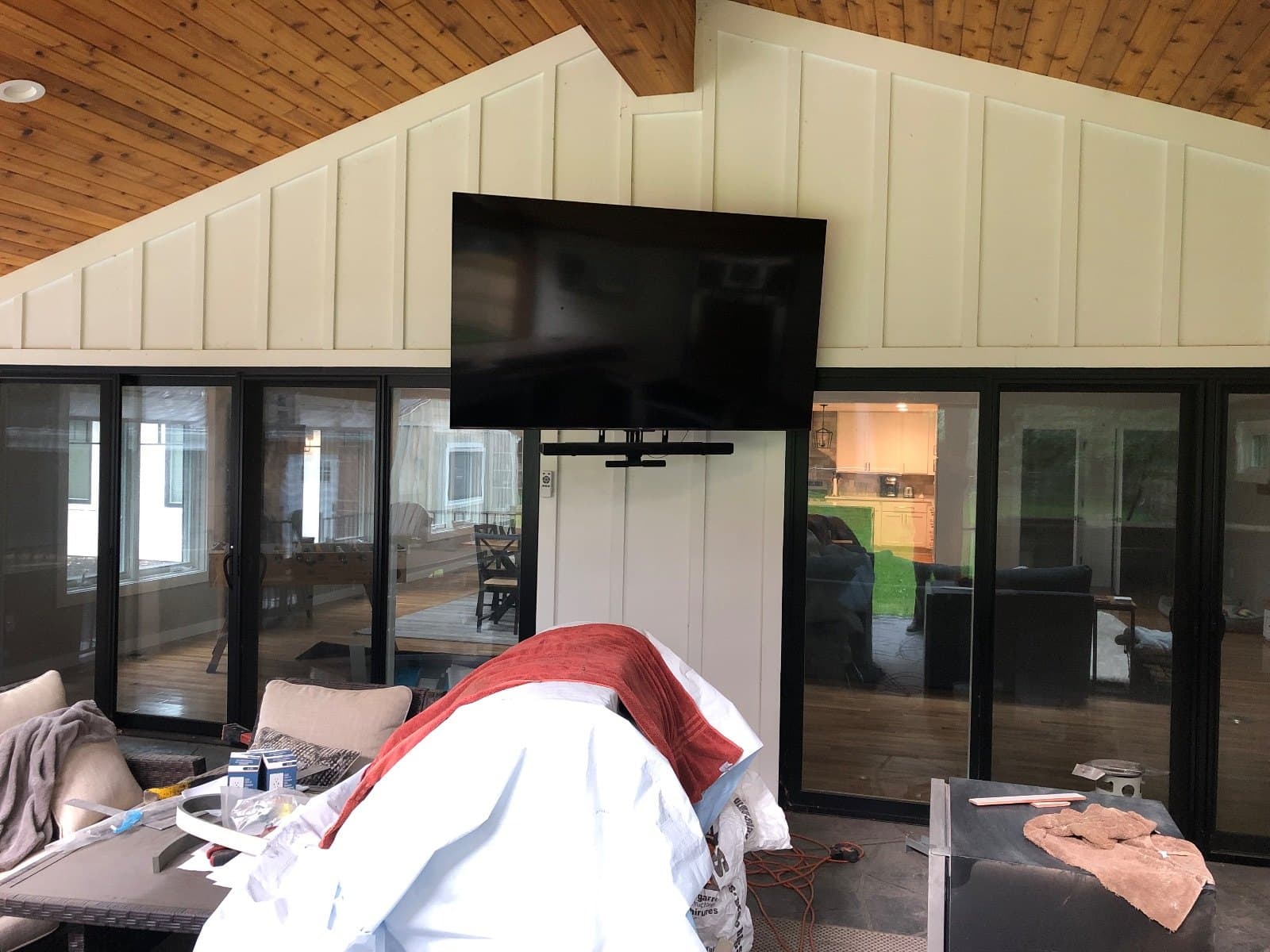 A wall of sliding glass panels in a finished room, ceiling boards overhead and a television on the far wall.