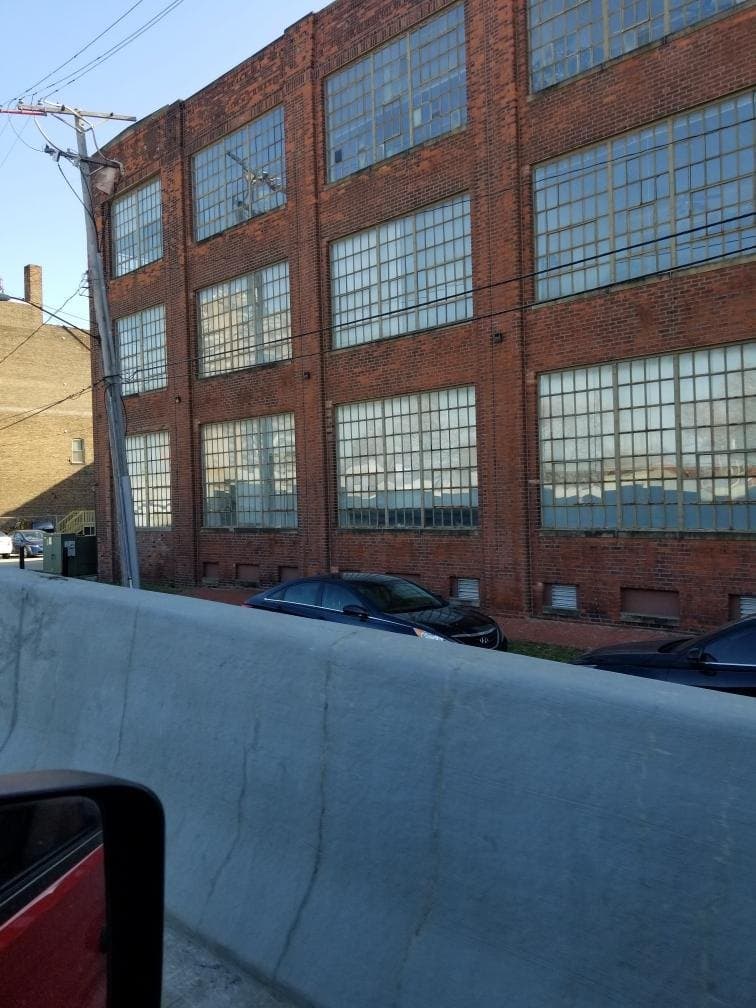 A brick industrial elevation with rows of steel windows running the length of it.