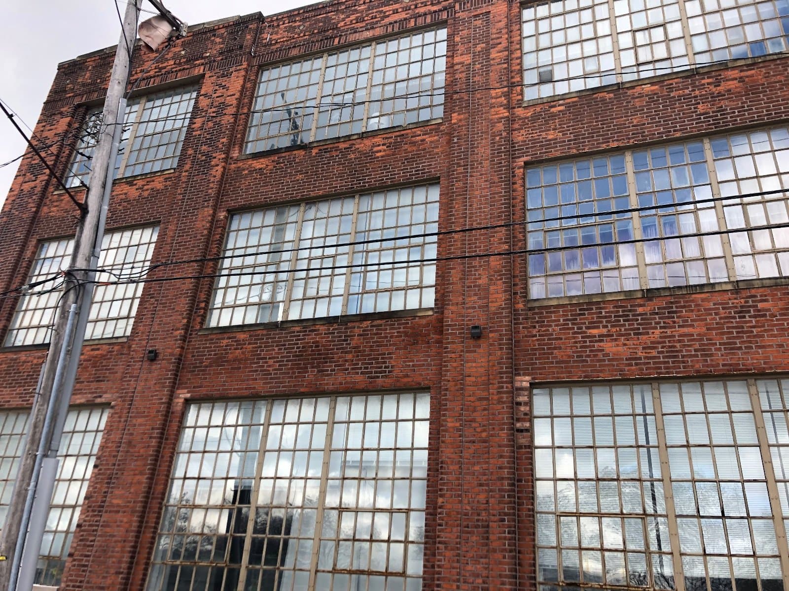 Steel windows in a brick industrial wall seen from below, several floors of divided lites.