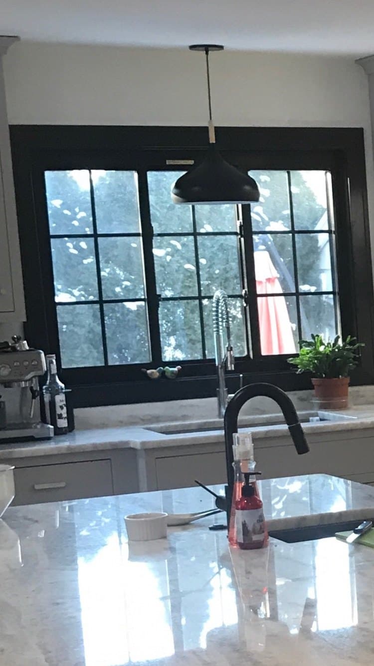 A kitchen window over the sink in a finished kitchen, pendant light alongside and the faucet in front of it.
