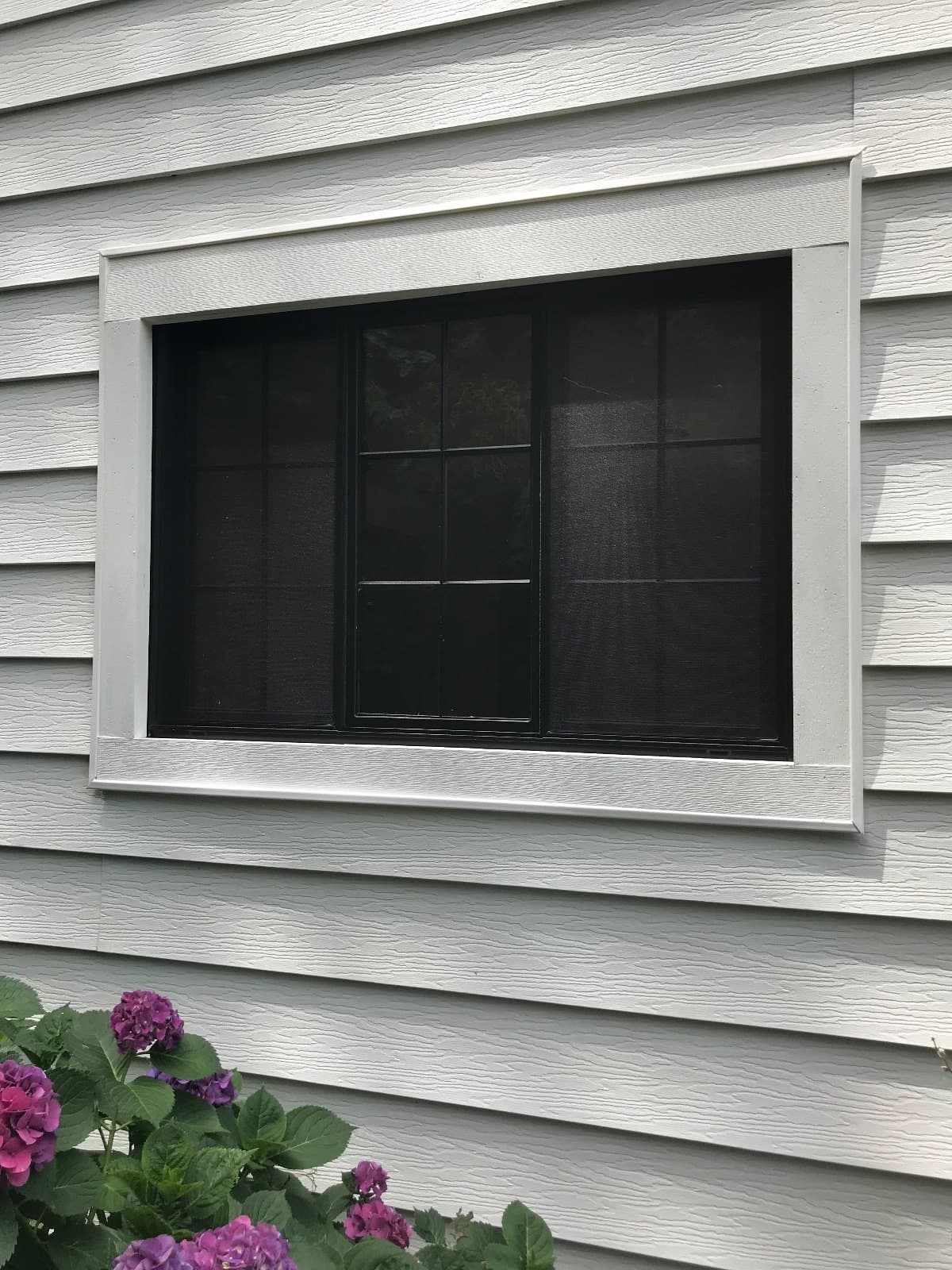 Black-framed window in gray lap siding, white trim.
