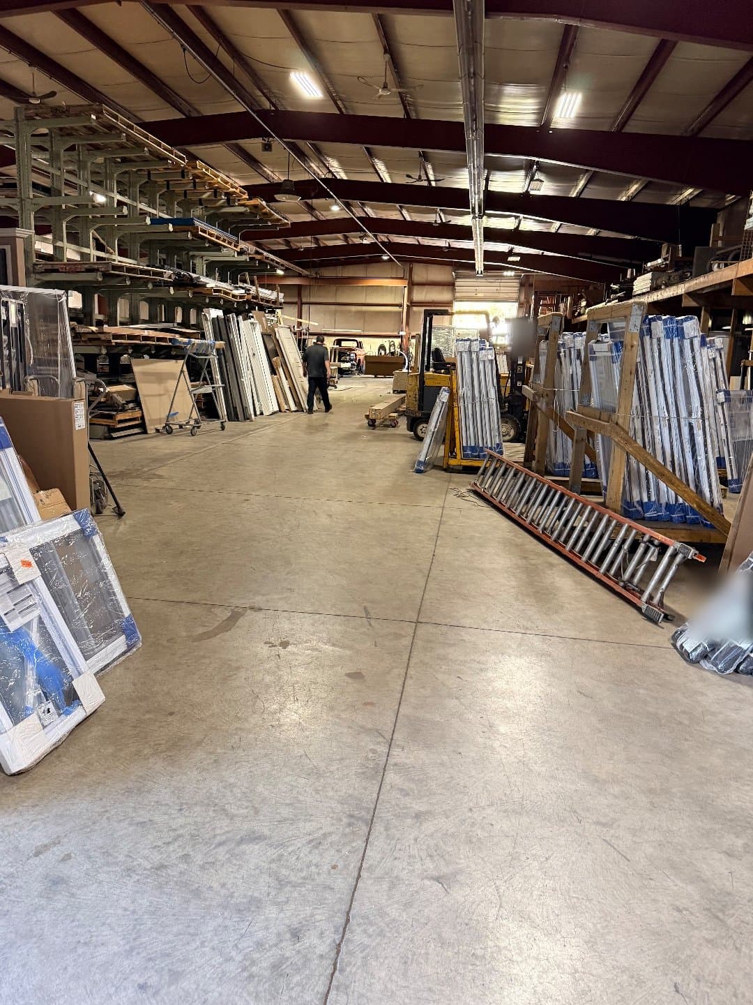 The main aisle of the D.W. Ross warehouse on West 63rd Street in Cleveland, wrapped vinyl windows leaning on the left and racked material on the right.