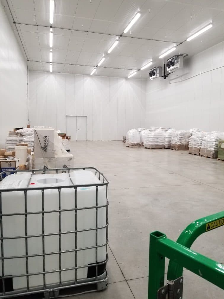 Finished cooler room with white panel walls and ceiling, lit and in use.