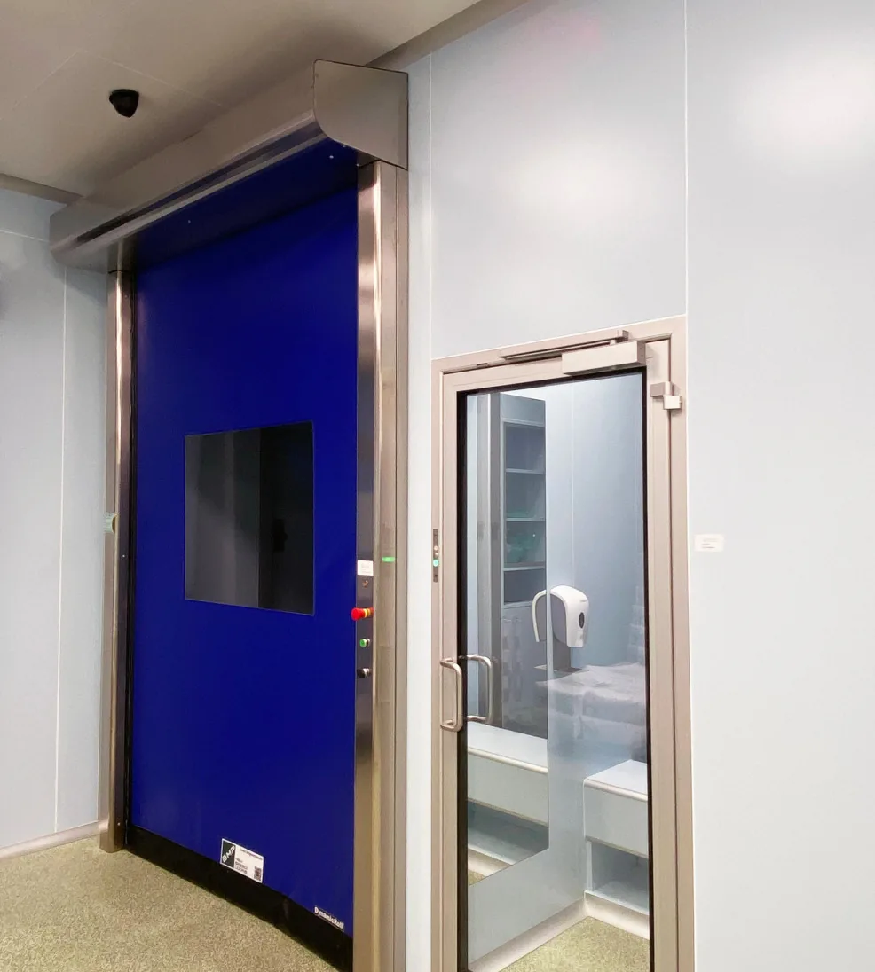 DynamicRoll CB 125 TM with a blue curtain beside a glazed cleanroom swing door