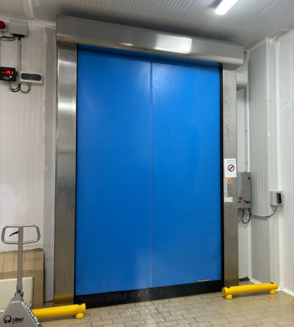 DynamicRoll Frigo 2 high-speed freezer door beside a pallet jack in a cold storage room