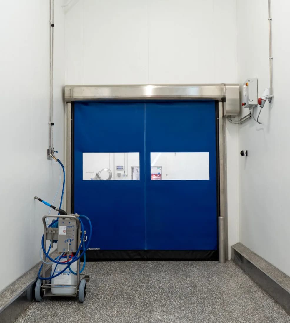Blue DynamicRoll high-speed roll-up door with vision strips in a narrow wash-down corridor