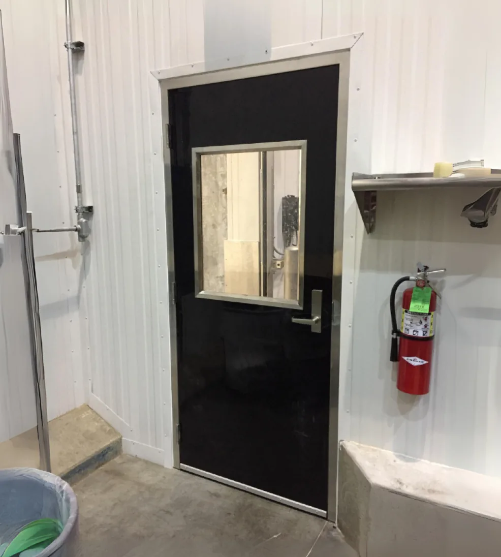Black Jamocor fiberglass swing door with a vision window in a wash-down room