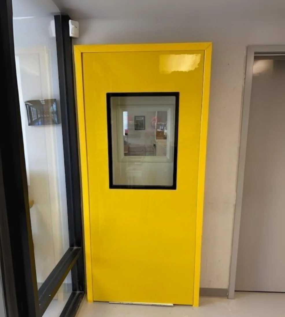 Yellow Jamocor fiberglass swing door with a large vision window