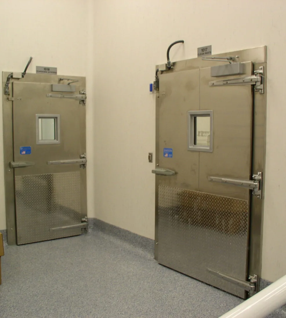 Two stainless steel Jamofoam I swing doors with vision windows and diamond-plate kick plates in a light corridor
