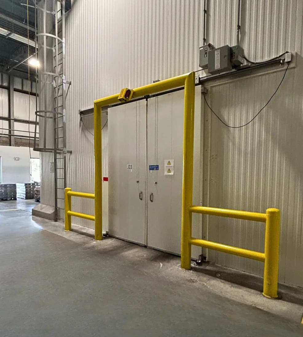 Power-operated Jamoglide bi-parting sliding doors framed by yellow guard rails at a dock