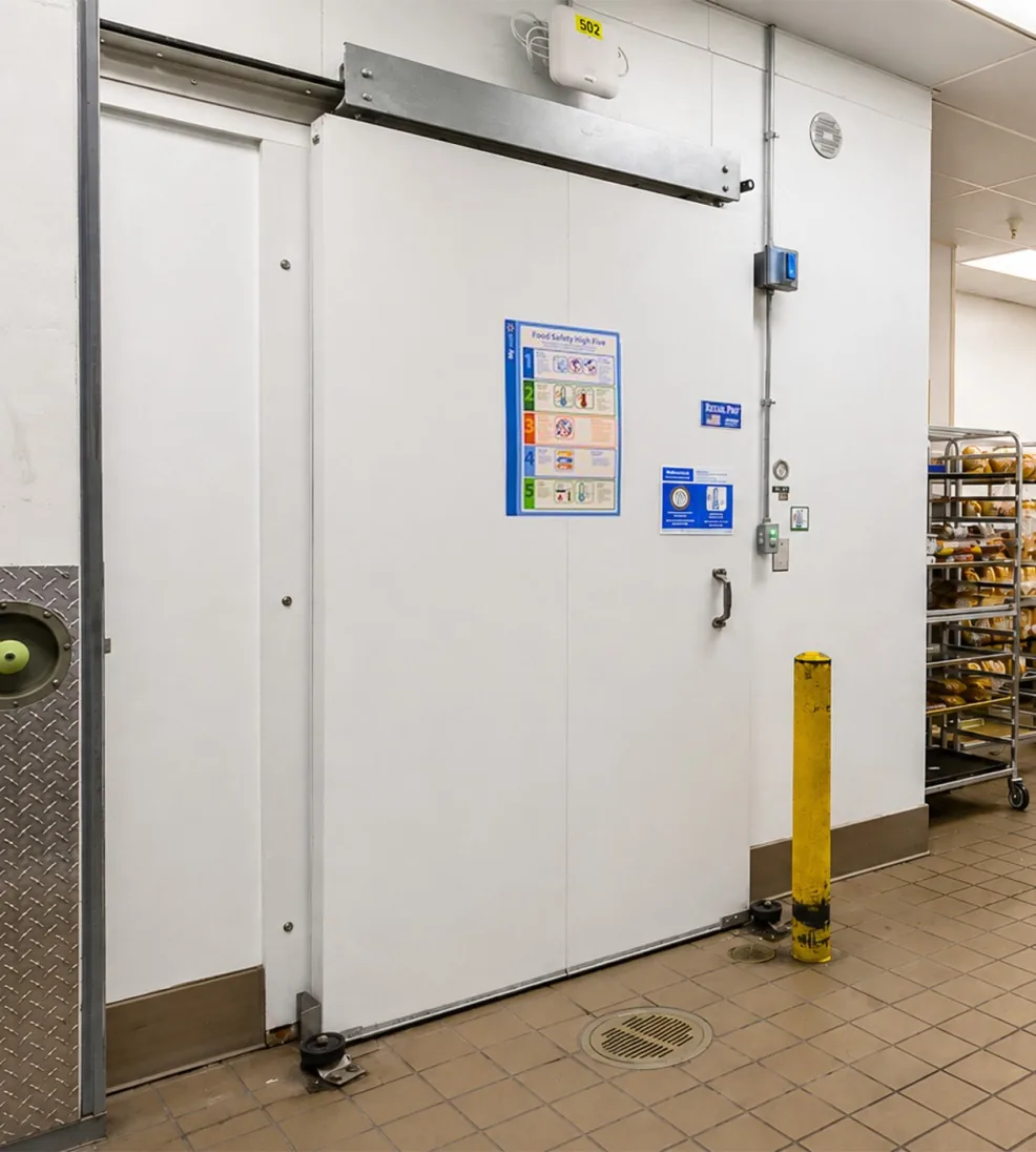 White Jamoglide Retail sliding door on a grocery back-room wall, closed