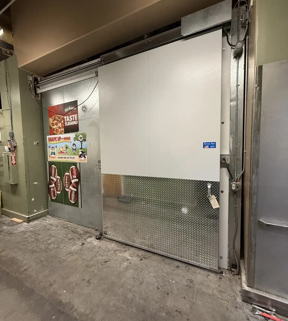 Jamoglide Retail sliding door with a diamond-plate lower panel in a store stock area