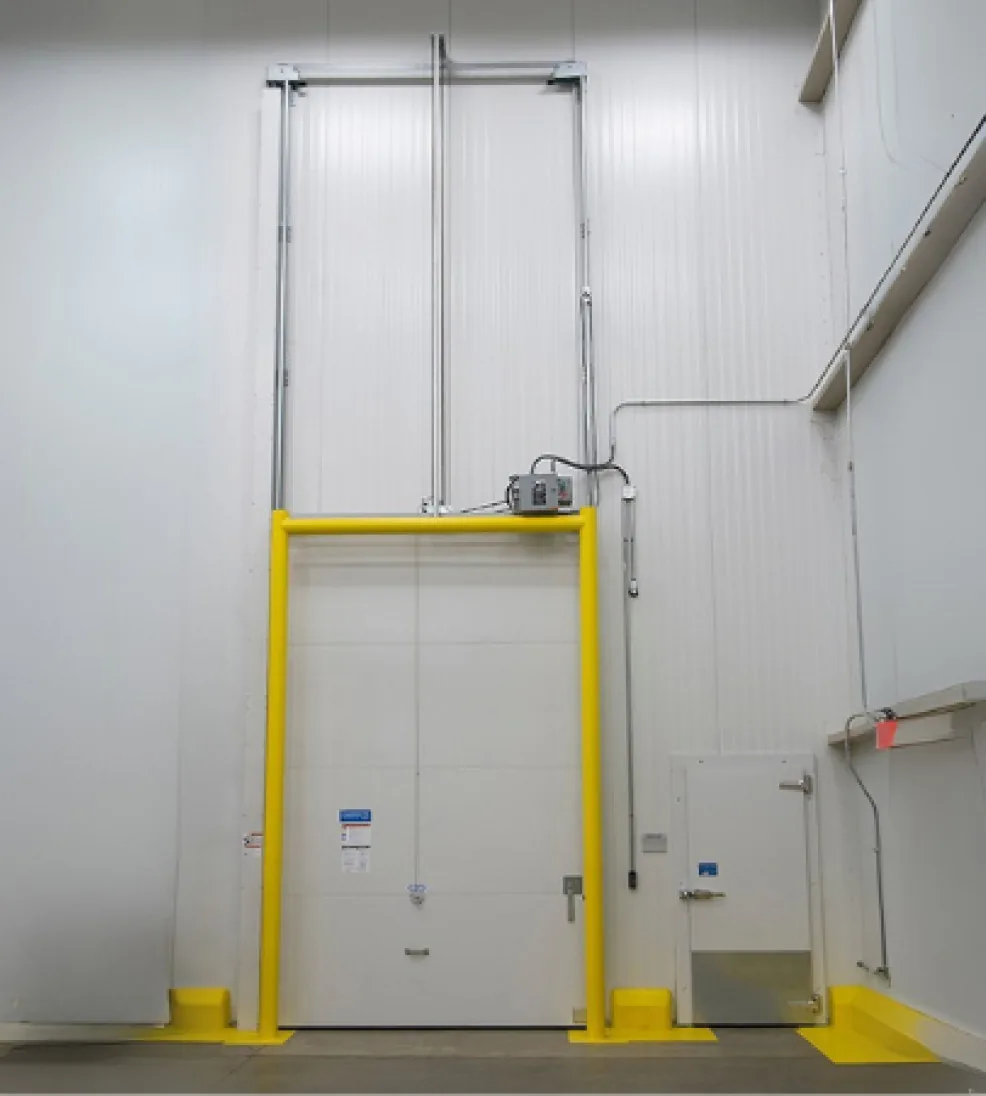 Jamoglide vertical sliding door with tall lift guides and a yellow guard frame in a high-bay cold room