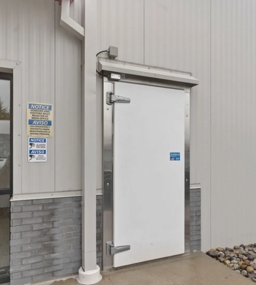 White Jamolite II fiberglass swing door with a stainless steel frame and hood beside a downspout