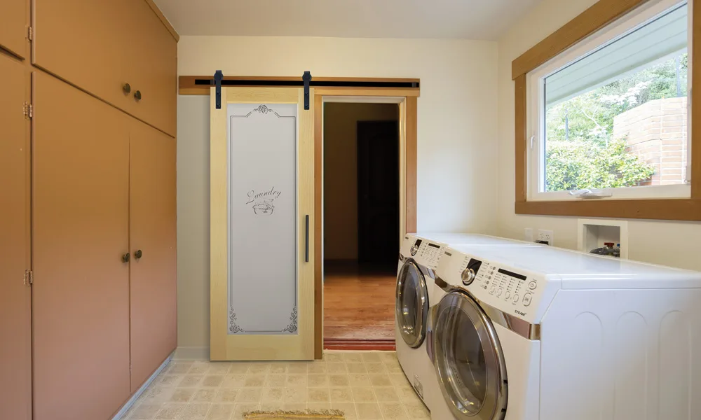 A barn door with a frosted glass panel, slid across a laundry room opening