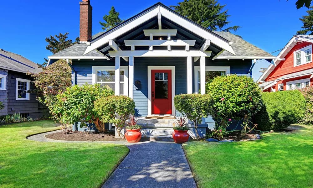 A red entry door with a glass lite on a blue craftsman bungalow
