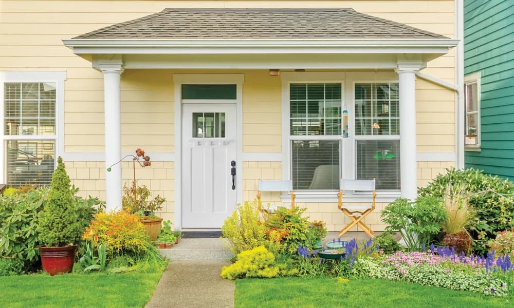A white craftsman entry door with a glass lite on a yellow house