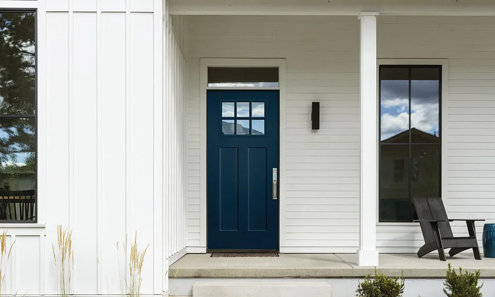 A navy craftsman entry door with a divided top lite on a white house