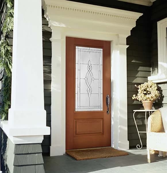 A wood-tone entry door with an oval-pattern decorative glass lite above a panel