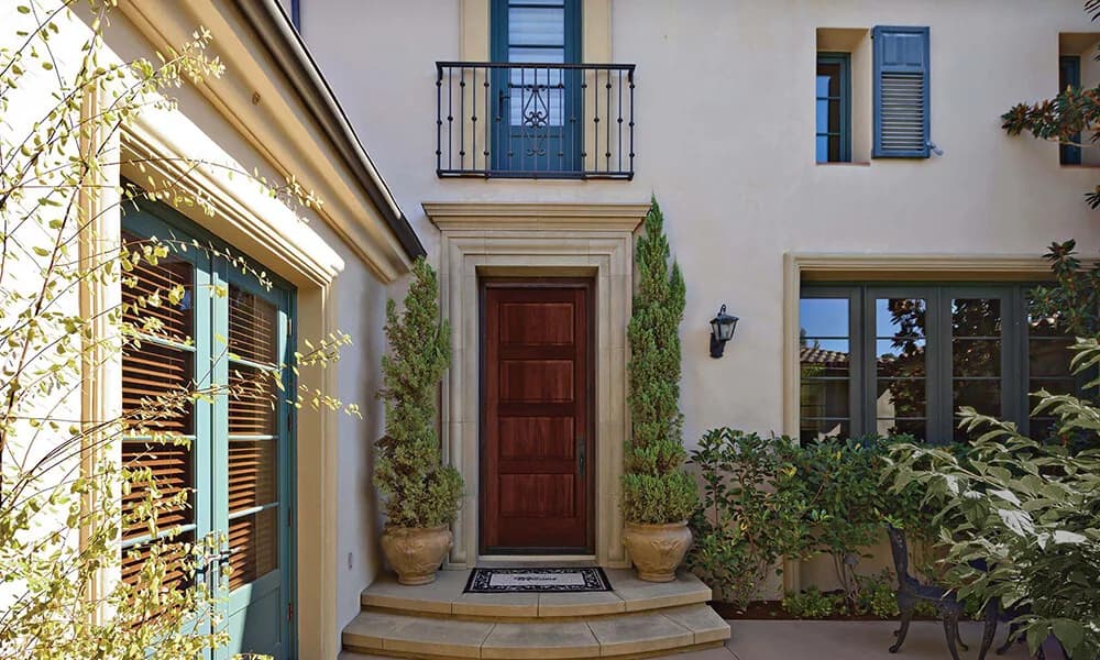 A red-brown fir-grain plank entry door on a stucco house