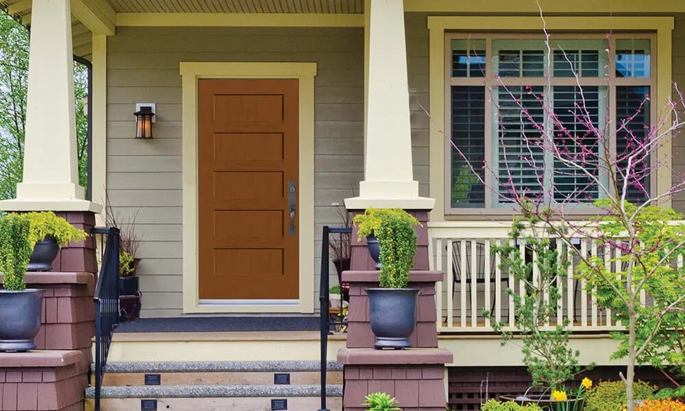 A stained fir-grain plank entry door on a green craftsman house