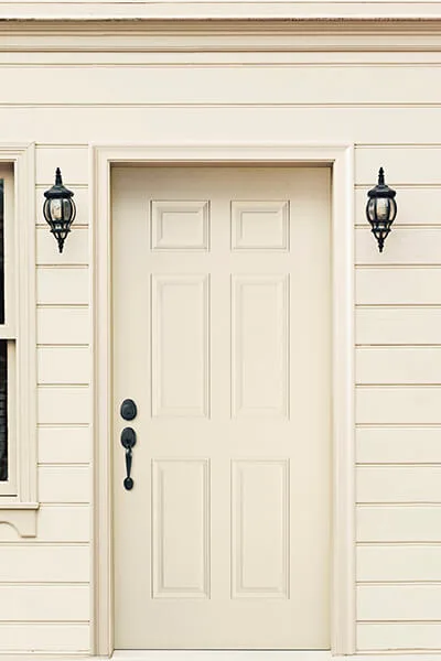A cream six-panel door between two wall lanterns