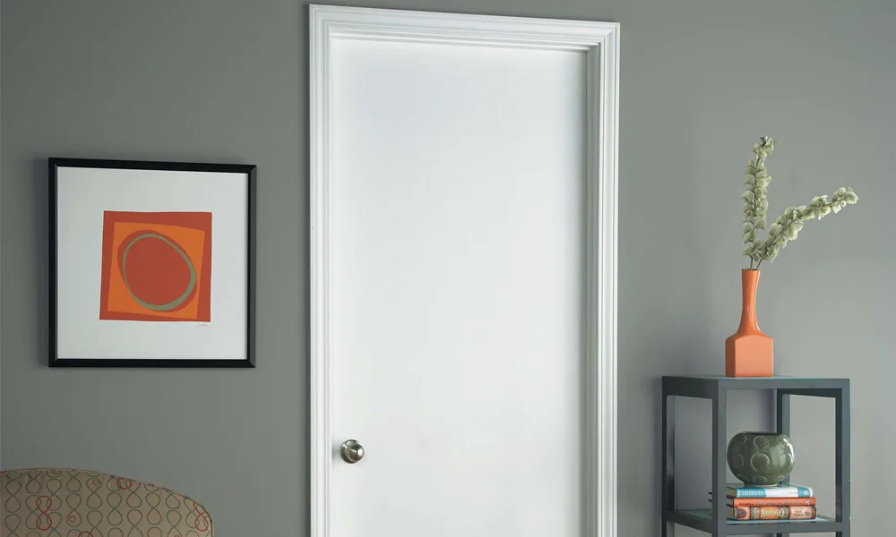 A white primed flush interior door beside framed art