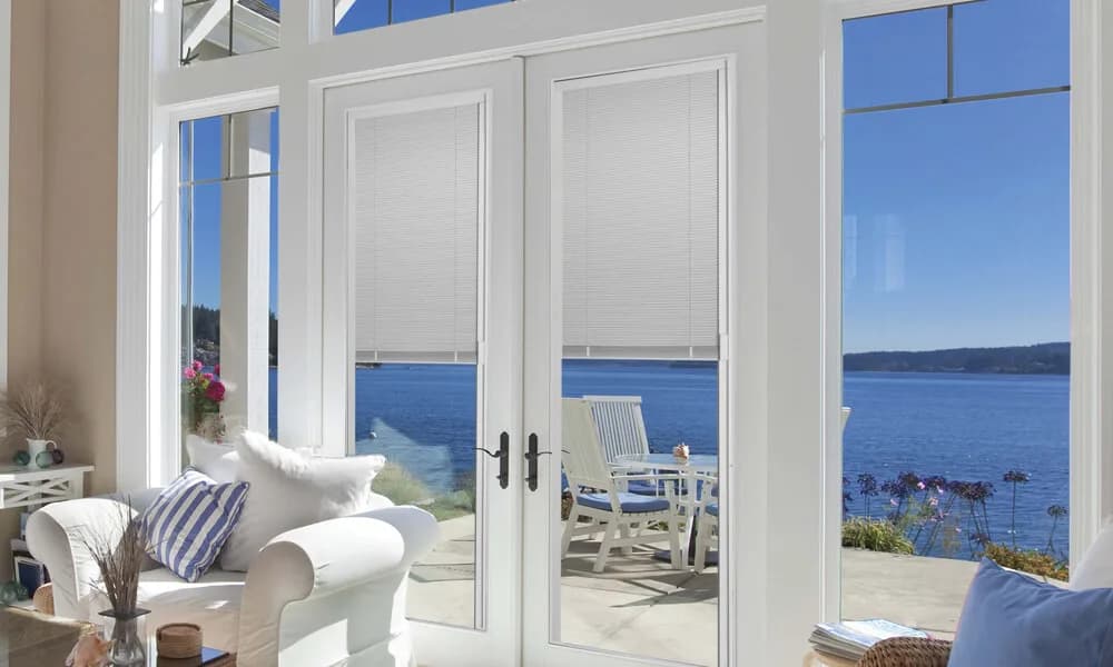 White French doors with blinds between the glass, opening to an ocean view